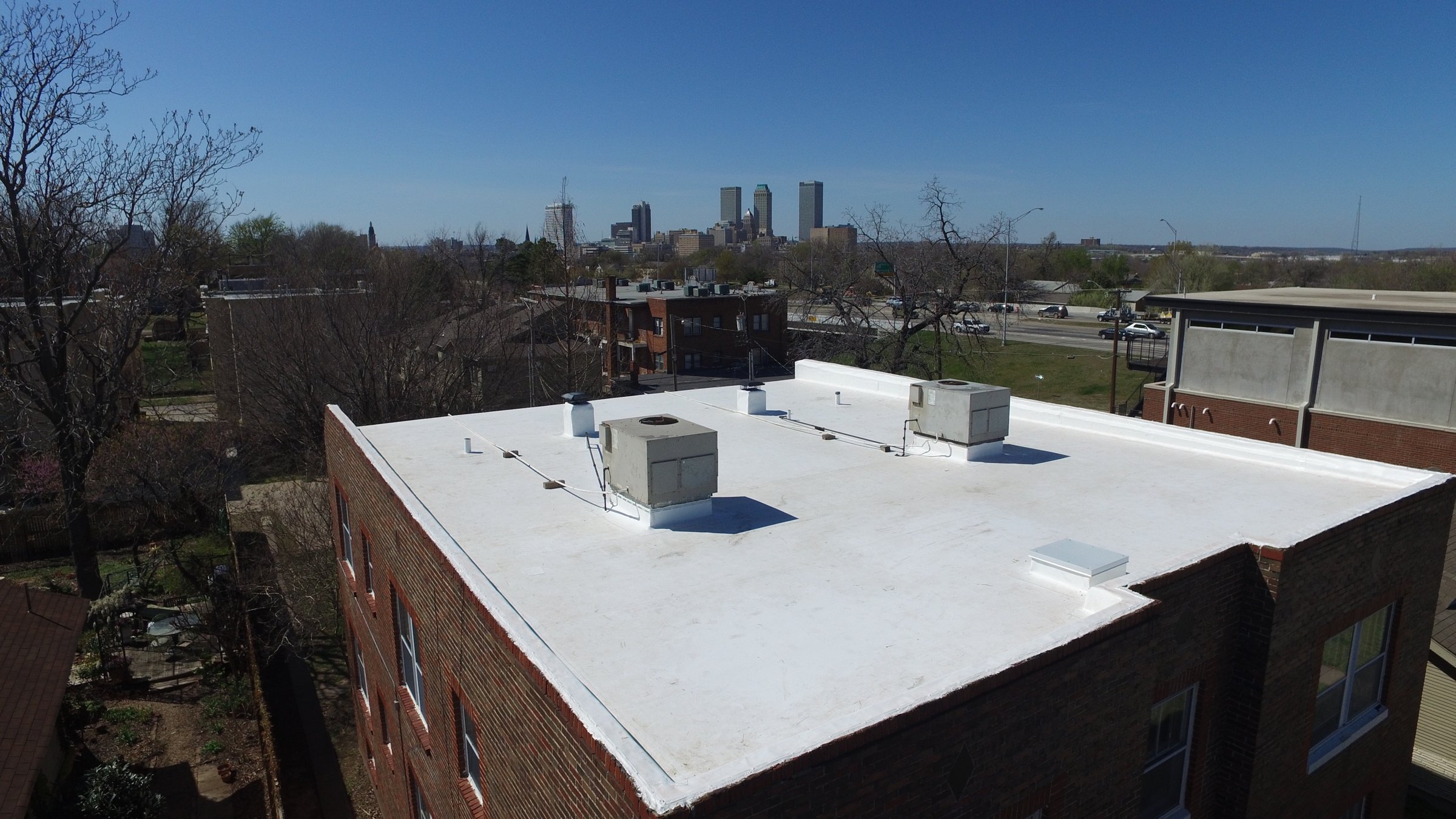 New white roof for Barry Properties at 15th and Peoria, with the Tulsa skyline behind