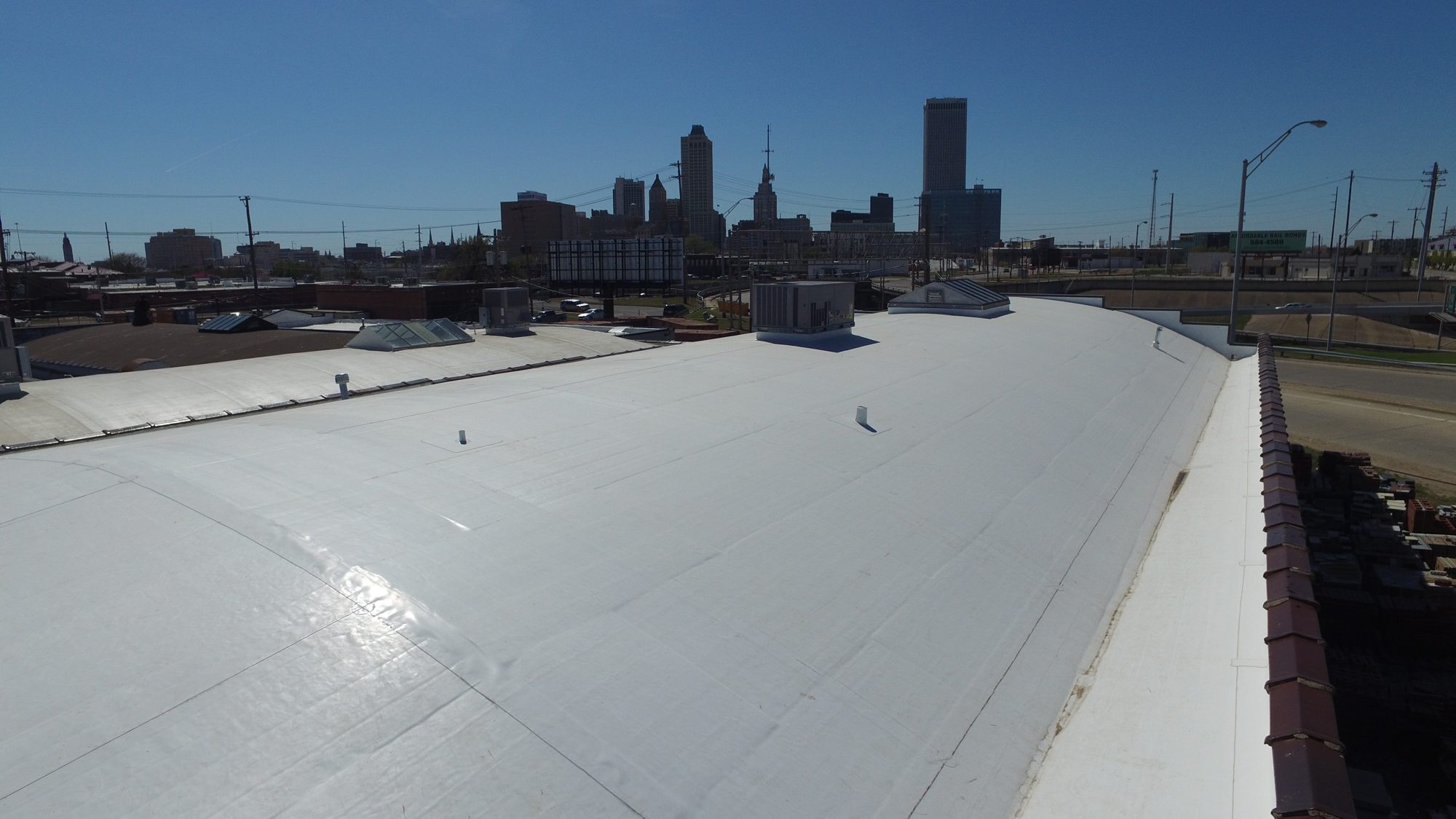White commercial roof on the Hawley building with the Tulsa skyline