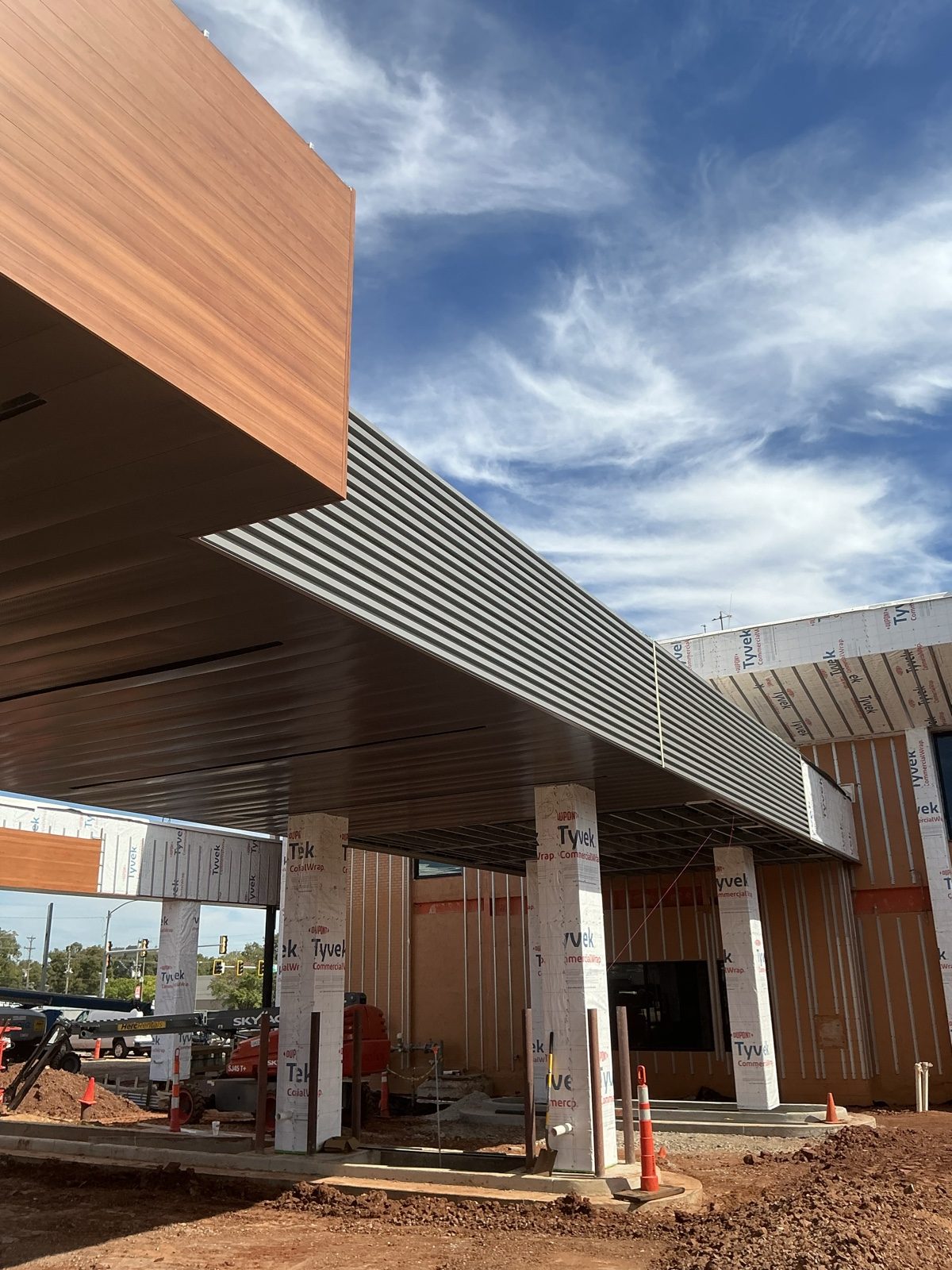 Canopy with wood-grain plank soffit and fascia over ribbed metal panels