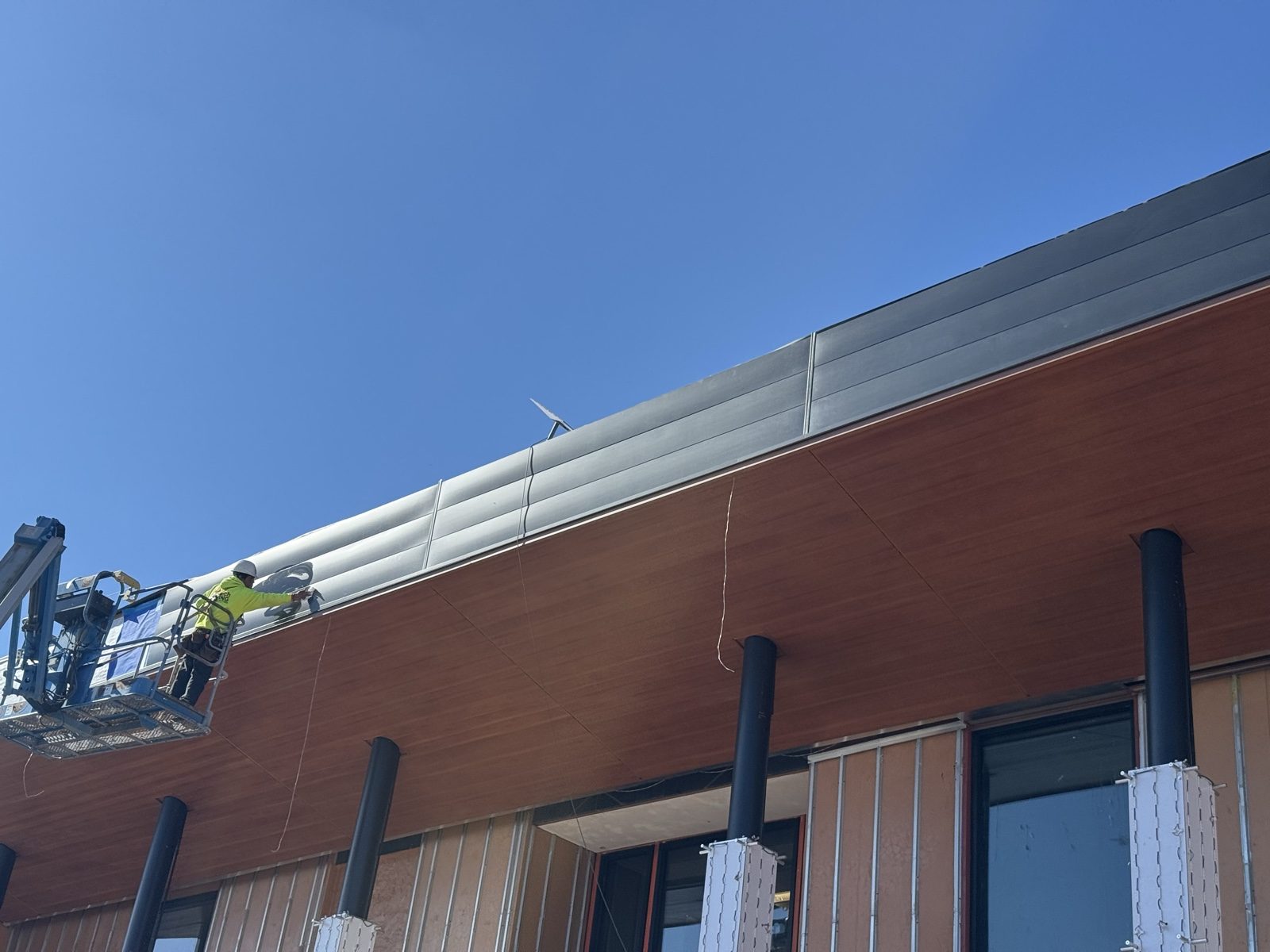 Our crew installing wall panels above wood-grain plank fascia