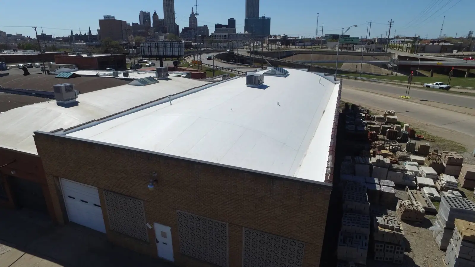 White roof on a warehouse with the Tulsa skyline