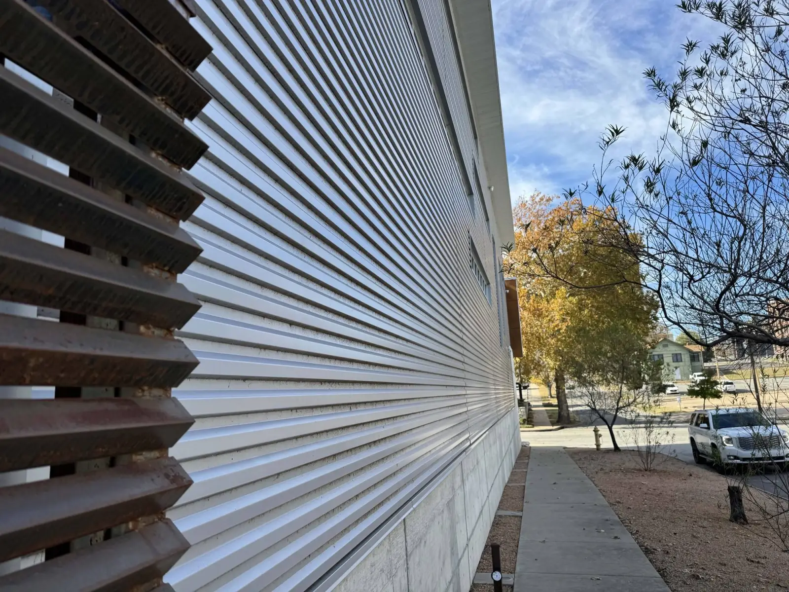 Corrugated metal wall panels with corten louvers